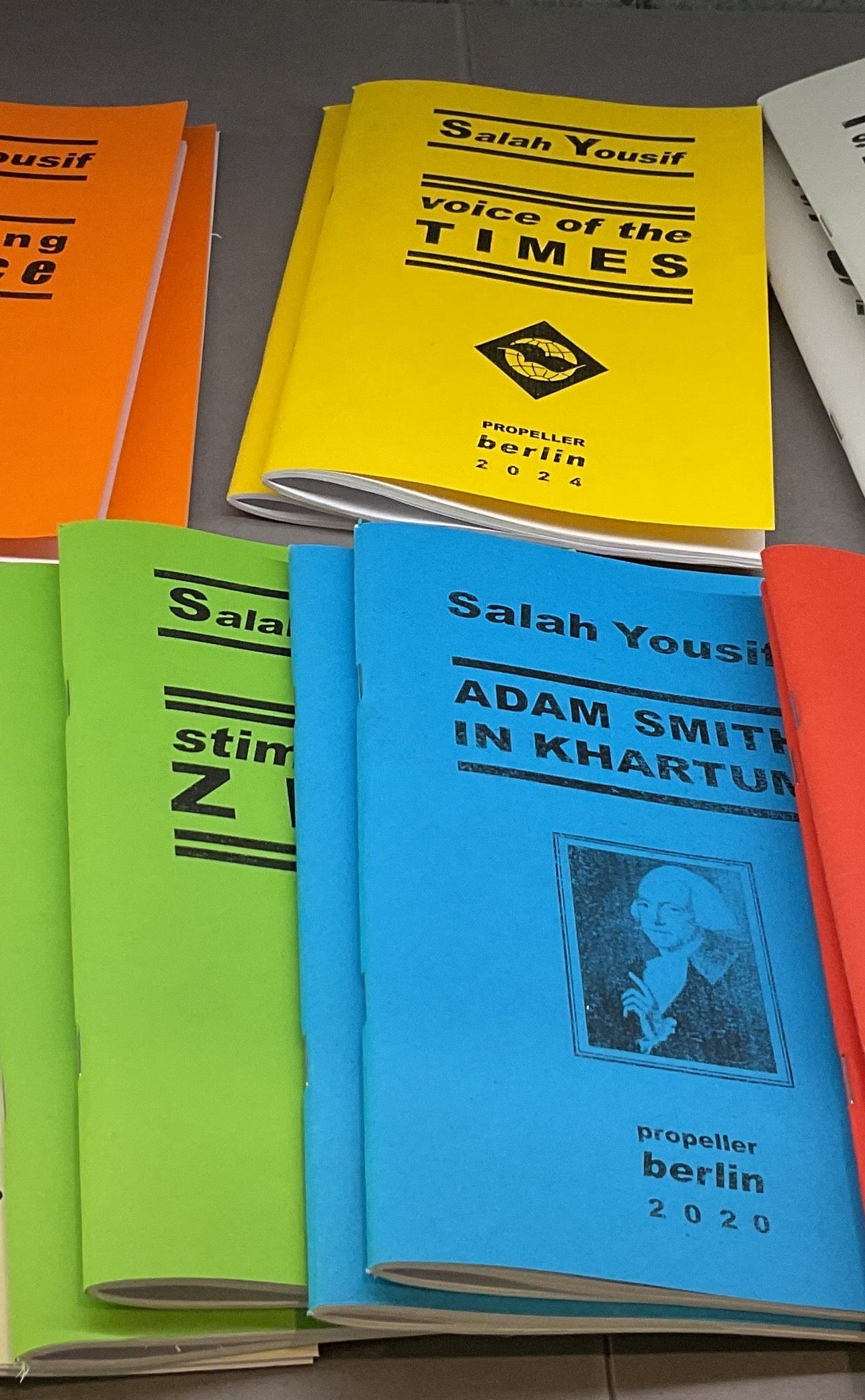 Collection of books with various colored covers in a shelf.